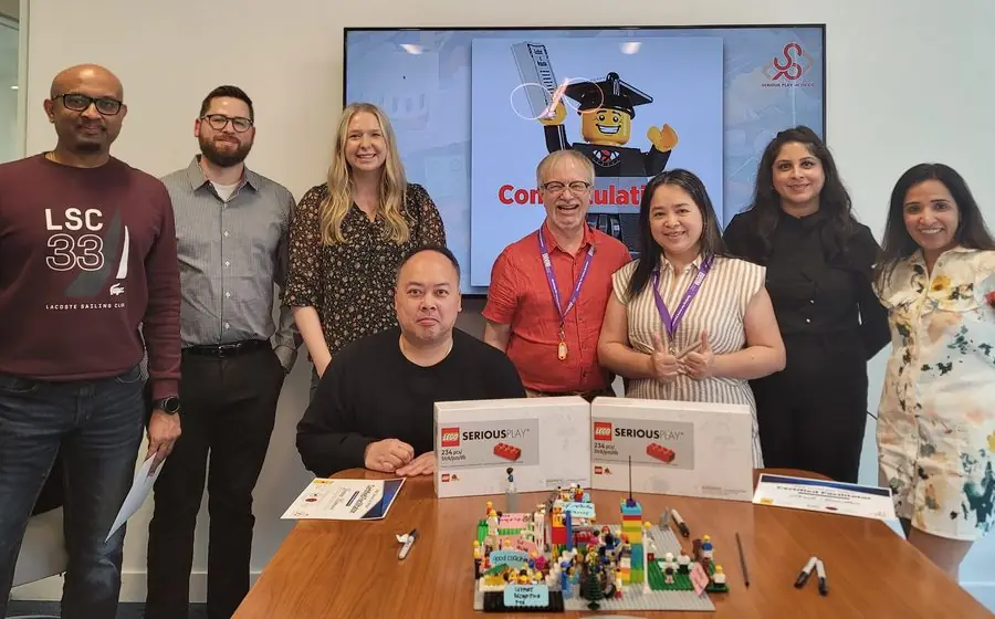 A cohort holding their LEGO Serious Play facilitator certificates at graduation